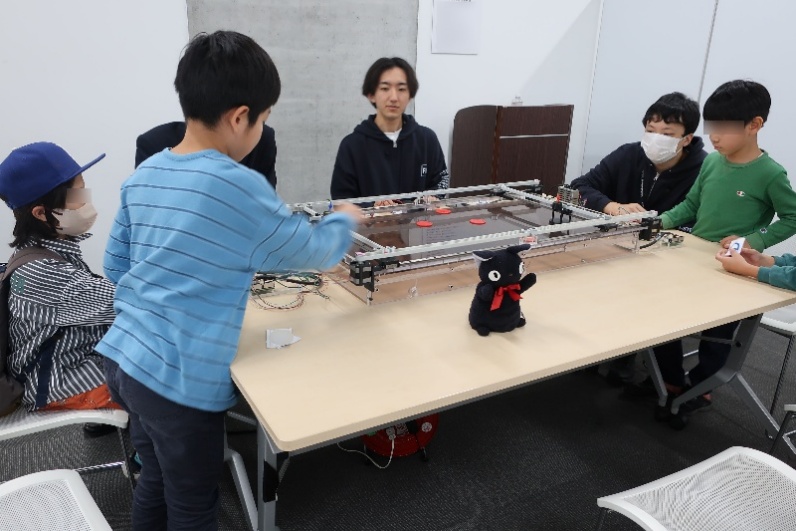 子どもたちが教育用の無線エアホッケーロボットを操作体験